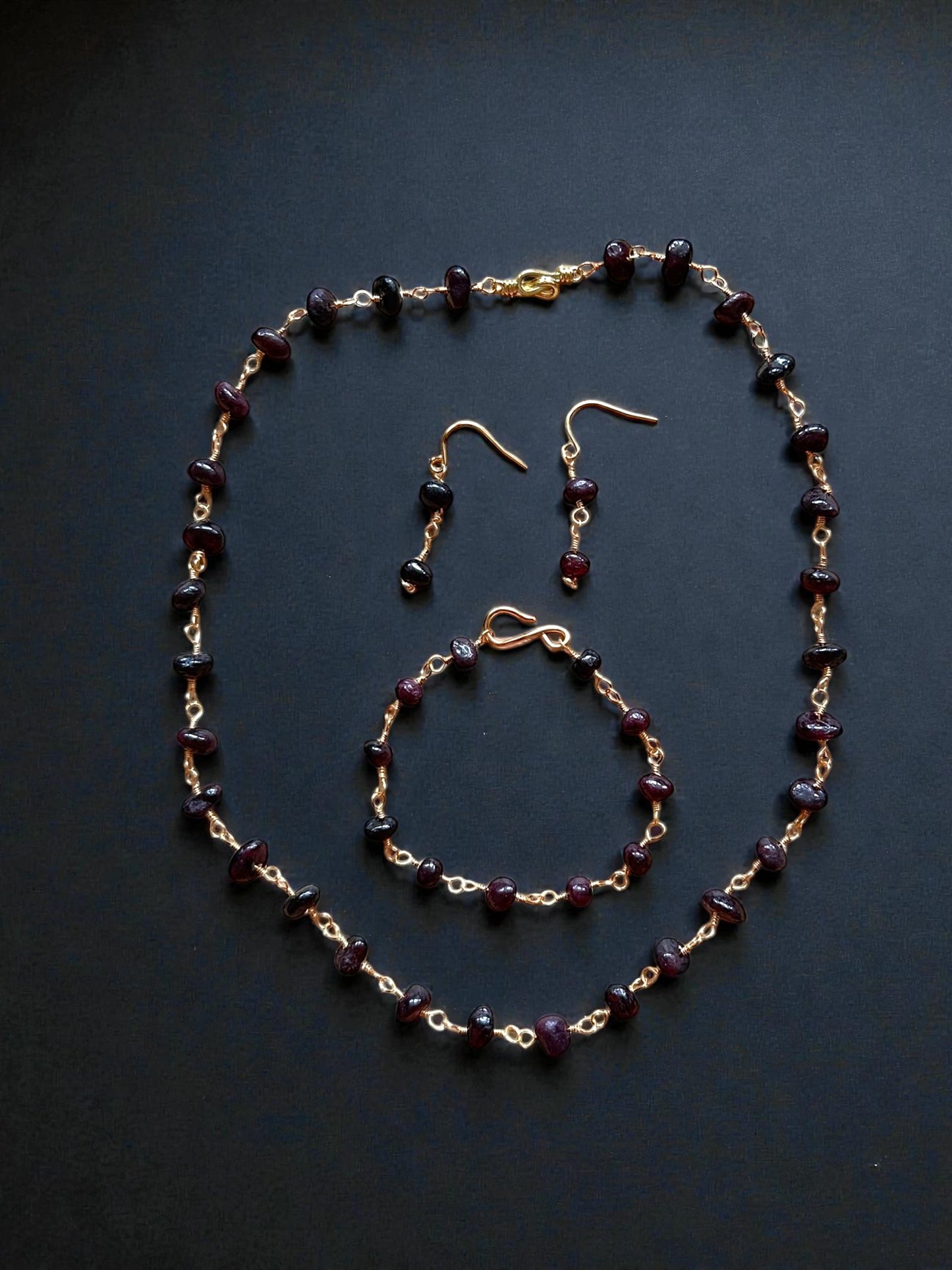 Entdecke unser antikes Granatperlen-Set, bestehend aus Kette, Ohrringen und Armband aus vergoldetem Kupfer. Alllerikerfreundliche Ohrhaken und zeitloses Design